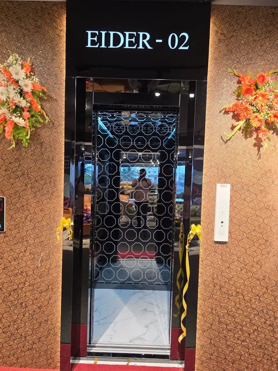 Lift entrance labelled EIDER-02 with decorative grille door